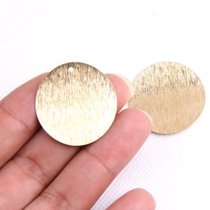 Puede incluir: Tres c&iacute;rculos de metal de color dorado con un acabado cepillado y un peque&ntilde;o agujero en el centro. Los c&iacute;rculos tienen un di&aacute;metro de aproximadamente 5 cm.