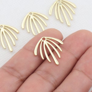 May include: Four gold metal decorative pieces shaped like a sunburst with a hole in the center. The pieces are on a white surface.