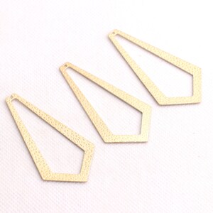 May include: Three gold-colored metal geometric shapes with a textured surface. The shapes are open and resemble a long, narrow diamond.