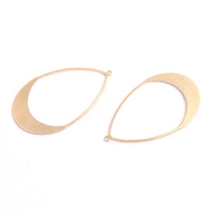 May include: Two gold-toned metal teardrop-shaped earring blanks with a rounded top and a jump ring.
