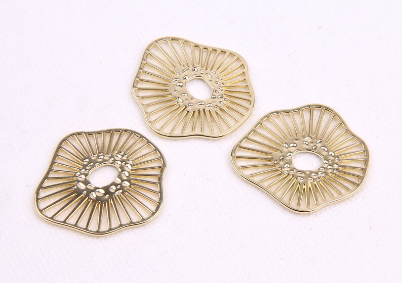 May include: Three gold-colored metal decorative pieces with a sunburst design and a textured center hole.