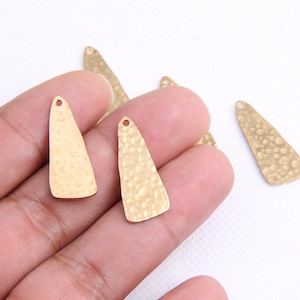 May include: Four gold-toned metal triangle-shaped charms with a hammered texture and a hole at the top for attaching to jewelry or other crafts.