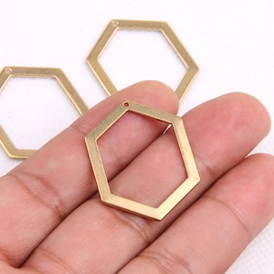 May include: Three gold-colored metal hexagonal shapes with a hole at the top. The shapes are arranged in a triangular pattern.