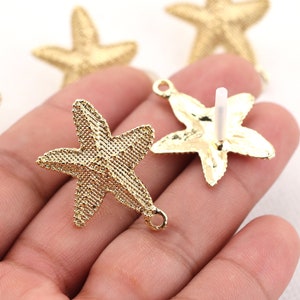 May include: Gold-tone metal starfish charms with a textured surface. The charms have a loop on the back for attaching to jewelry or other crafts.