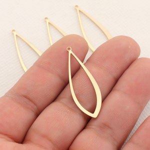 May include: Four gold-colored metal teardrop-shaped earring blanks with a hole at the top.