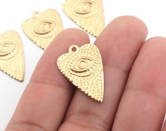 May include: Four gold-colored heart-shaped charms with an evil eye design. The charms are textured and have a raised eye design.