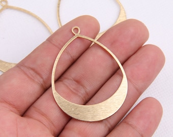 May include: Gold-toned metal earring blanks in the shape of a teardrop with a rounded top and a flat bottom. The blanks have a brushed finish and a small loop at the top for attaching earring findings.
