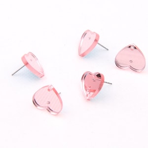 May include: Four pairs of pink heart-shaped stud earrings. The earrings are made of acrylic and have a shiny finish.