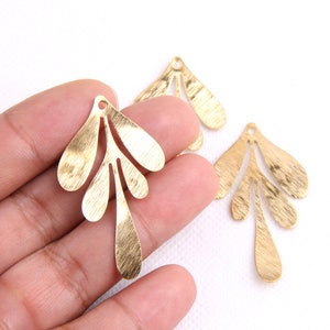 May include: Three gold-colored metal leaf-shaped charms with a textured surface. The charms have a hole at the top for attaching to jewelry or other crafts.