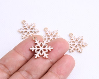 Puede incluir: Cuatro abalorios de copo de nieve de color dorado con esmalte blanco. Los copos de nieve tienen una forma de estrella de seis puntas con detalles intrincados.