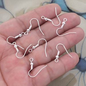 May include: Six silver earring hooks with a small ball at the top of each hook.