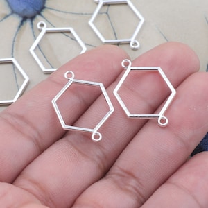 May include: Silver hexagon shaped pendant blanks with jump rings. These blanks are perfect for adding your own charms, beads, or other embellishments.