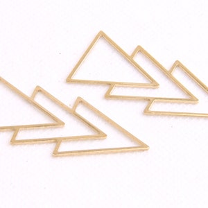 May include: Set of six gold-toned metal triangle shapes. The triangles are layered on top of each other, creating a geometric design.