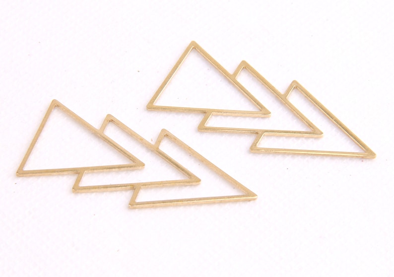 May include: Set of six gold-toned metal triangle shapes. The triangles are layered on top of each other, creating a geometric design.