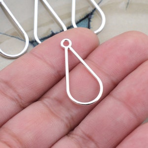 May include: Silver-colored teardrop-shaped jewelry findings. The open-backed pendants have a small loop at the top for attaching to a chain or other components. These findings are ideal for creating earrings or pendants.