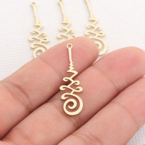 May include: Three gold-colored metal charms with a decorative design. The charms are shaped like a long, thin rectangle with a spiral at the bottom. The charms have a hole at the top for attaching to a necklace or bracelet.