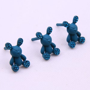 May include: Three teal blue bunny-shaped earrings with rhinestones. Each earring has a post for piercing.