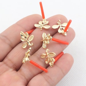 May include: Gold-coloured leaf-shaped jewellery findings with red posts. The findings have detailed leaf vein patterns. The image shows several of these findings, likely for earrings or other jewellery making projects.