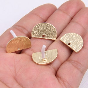 May include: Four gold-colored metal half-circle shapes with a hole in the center. The shapes have a textured surface.