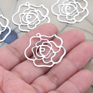 May include: Five silver metal rose-shaped charms with a delicate, intricate design. The charms are perfect for jewelry making, scrapbooking, and other craft projects.