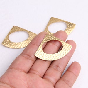 May include: Three gold-toned metal earring blanks with a hammered texture and a rounded oval opening. The blanks are in the shape of a half-circle.