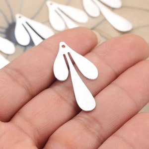 Puede incluir: Encantos para pendientes de metal plateado en forma de flor estilizada con tres pétalos. Los encantos tienen un agujero en la parte superior para sujetarlos a joyas.