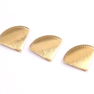 May include: Three gold-colored metal fan-shaped charms with a textured surface and a hole at the bottom.