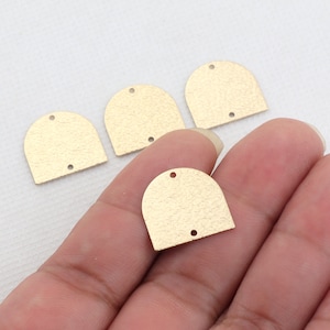 May include: Four gold-colored metal arch shapes with a textured surface. The arches have a hole at the top for hanging.