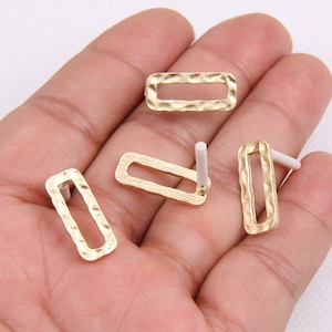 May include: Four gold-toned metal earring blanks with a textured surface. Each blank has a rectangular shape with a hole at the top for attaching an earring finding.