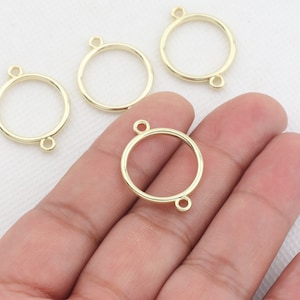 Könnte beinhalten: Vier goldfarbene Metall-Kreis-Anhänger mit Sprungringen. Jeder Anhänger hat eine glatte, runde Form und eine polierte Oberfläche.