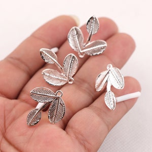 Puede incluir: Cuatro abalorios de plata en forma de hoja con un bucle en la parte superior para sujetarlos a joyas u otras manualidades.