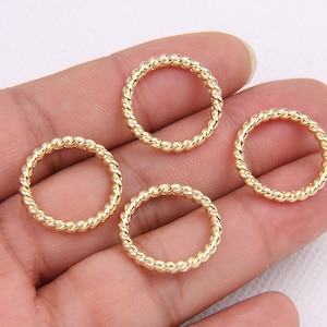 May include: Four gold-coloured, twisted wire rings. The rings are all the same size and are arranged in a semi-circle on a hand.