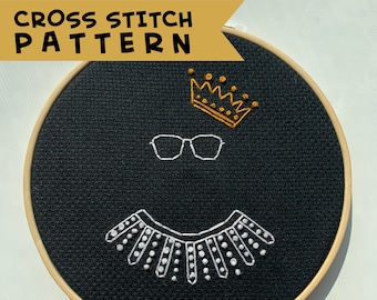 May include: Cross stitch pattern of a black and white portrait of Ruth Bader Ginsburg, featuring her iconic glasses and lace collar. The pattern is displayed on a black fabric in a wooden embroidery hoop.