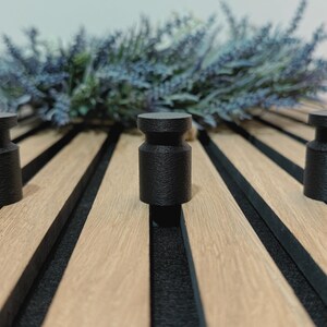 Minimalist knob hook for slatted acoustic panels, easy to install without screws or drilling, ideal for modern interiors.