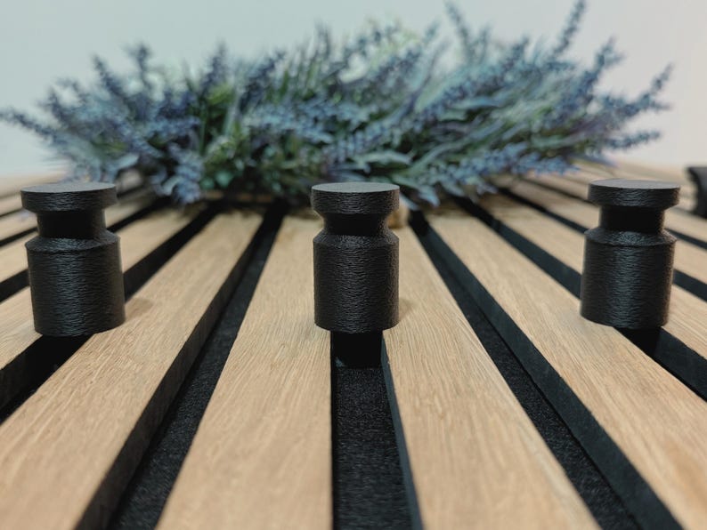 Minimalist knob hook for slatted acoustic panels, easy to install without screws or drilling, ideal for modern interiors.
