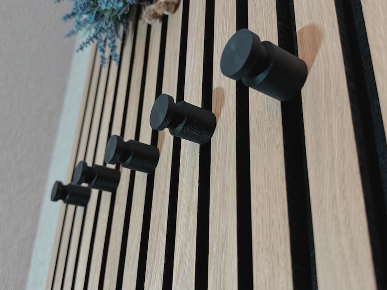 Minimalist knob hook for slatted acoustic panels, easy to install without screws or drilling, ideal for modern interiors.