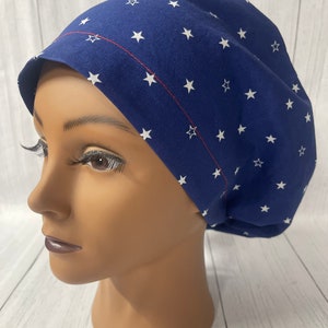 Puede incluir: Un gorro de quirófano azul con un patrón de estrellas blancas y una costura roja alrededor del borde.