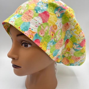 May include: A green, yellow and pink patterned surgical scrub hat with bunnies and Easter eggs.