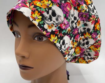 May include: A black scrub hat with a colorful floral and skull print. The hat has a tie at the back.