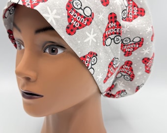 May include: A gray and red patterned scrub hat with the text "Oh, Fudge!" repeated throughout. The hat has a white snowflake pattern and a red and black plaid design.
