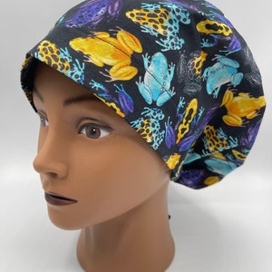 May include: A black scrub hat with a colorful frog print. The frogs are yellow, blue, and purple with black spots.