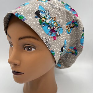 May include: A gray scrub hat with a white star pattern and a cartoon image of a group of people. The text "The Jetsons" is printed on the hat.