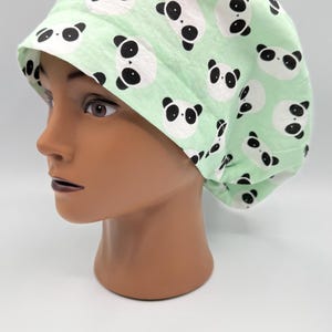 Può includere: Un cappuccio chirurgico verde chiaro con un motivo ripetuto di facce di panda in bianco e nero. Il cappuccio è realizzato in un tessuto morbido ed è progettato per coprire i capelli. Il motivo panda aggiunge un tocco giocoso all'accessorio medico.