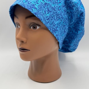 May include: A blue scrub hat with a white and blue patterned design. The hat is made of a soft, comfortable fabric and is perfect for healthcare professionals.
