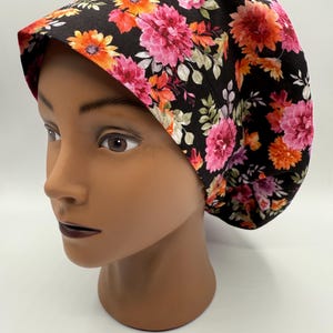 May include: A black scrub hat with a floral print featuring pink, orange, and green flowers. The hat has a tie at the back.