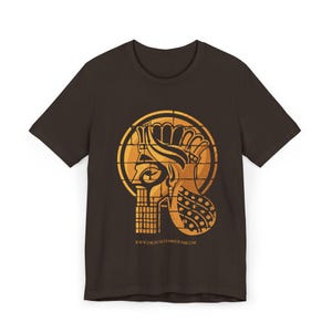 May include: A dark brown short-sleeve t-shirt featuring a large, circular, orange graphic of a stylised ancient profile wearing a crown. The design includes a grid-like pattern and the text WWW.DIGITALHAMMURABI.COM printed in small letters below.