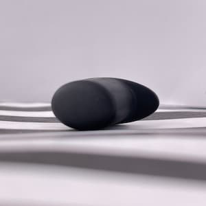 May include: A black silicone earbud with a rounded shape.