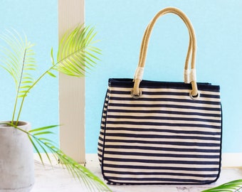 May include: A striped black and white tote bag with tan rope handles. The bag is made of canvas and has a casual, beachy style.