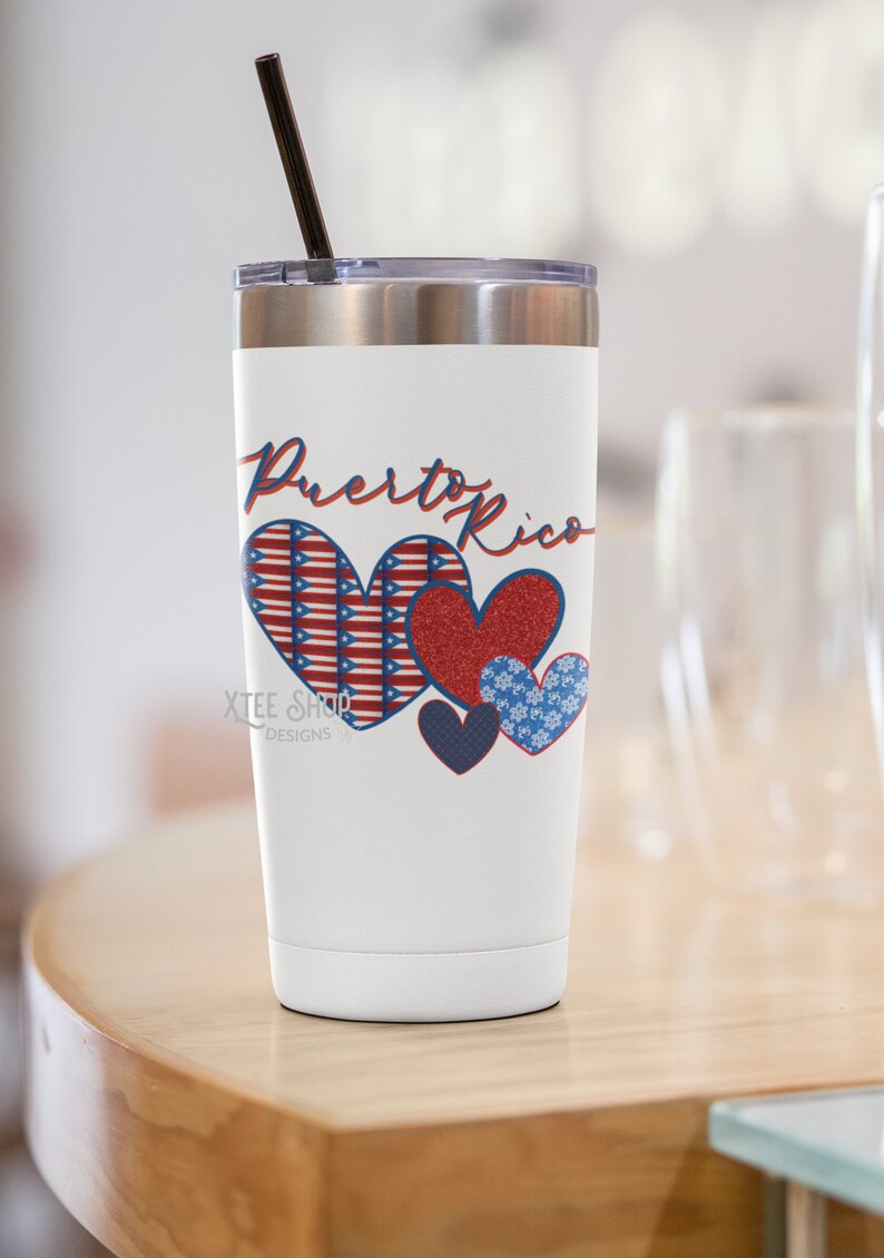 May include: White insulated travel mug with a black straw and a silver lid. The mug features the words "Puerto Rico" in red script above four heart designs. The hearts are red, blue, and white with patriotic patterns.