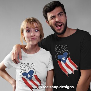 May include: Two people wearing t-shirts with a white outline of a stylized coqui frog holding a heart with a star inside. The heart is draped with a red, white, and blue Puerto Rican flag. The text "xtee shop designs" is at the bottom of the image.